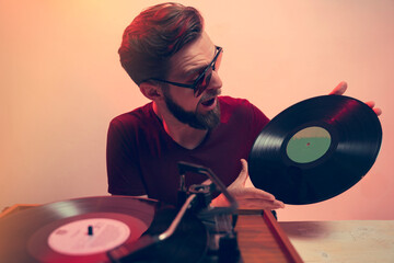 Retro style image, exited guy holding vinyl rerord in front of turntable 