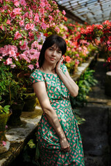 A brunette in a green dress among blooming azaleas