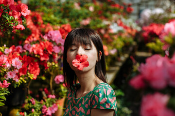 A brunette in a green dress among blooming azaleas