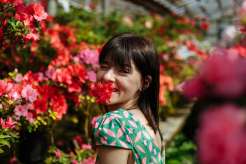 Naklejka premium A brunette in a green dress among blooming azaleas