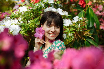 Fototapeta premium A brunette in a green dress among blooming azaleas