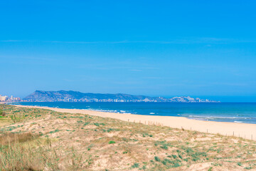 A beach with a view of the city of Cullera in the distance