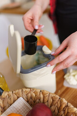 Female hand put bokashi bran in a compost container for fermentation. Woman recycling organic food leftovers in a composting bin at home