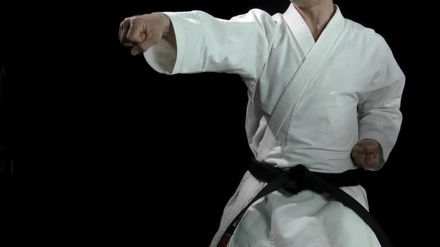 On a black background, an adult and a small athlete perform punches