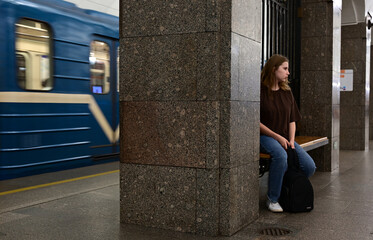 a girl with a backpack is waiting for a train at the station