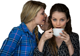 Woman whispering into other woman ear while having a cup of coffee