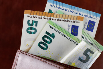 Euro banknotes stick out of the wallet
