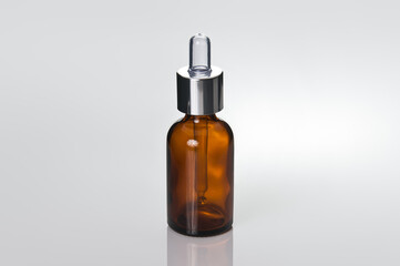Glass brown transparent dropper bottle. Close-up, photo on a reflective surface.