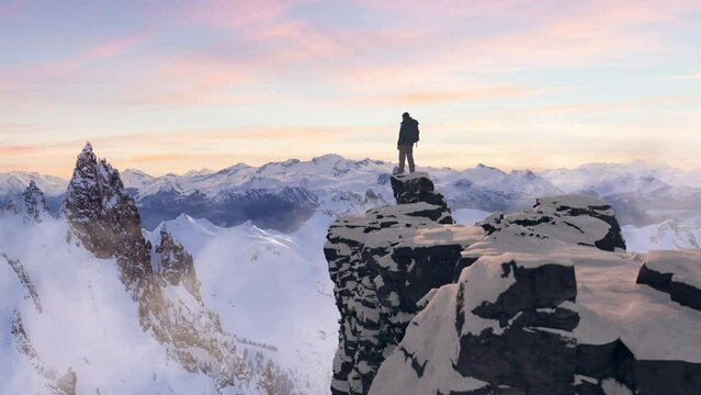 Adventurous Man Hiker standing on top of icy peak with rocky mountains in background. Adventure Composite. 3d Rendering rocks. Aerial Image of landscape from BC, Canada. Sunset Sky. 3D Illustration