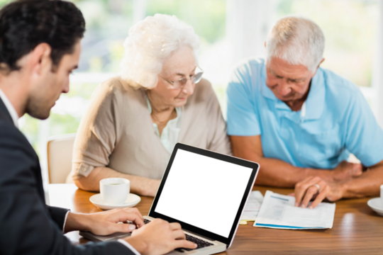 Businessman using laptop while senior couple is reading documents
