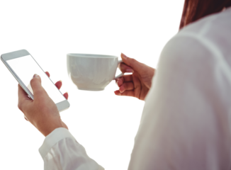 Woman with red hair using smartphone and holding coffee cup 