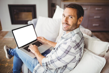 Young man holding laptop and sitting on sofa