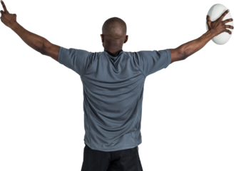 Rear view of sportsman with arms raised holding rugby ball