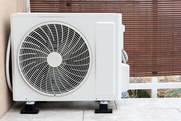 White air conditioner standing on the balcony. Air conditioning on hot days. Device with a fan to fight the heat. Home electronics for changing temperature.