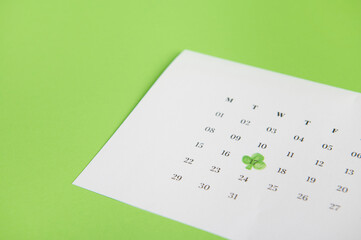 Still life with a white calendar marked with the date March 17- traditional Irish festival - Saint Patrick's Day, celebrated in Ireland, isolated on green background with free advertising space
