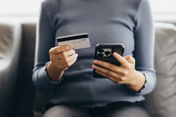 Close up of young woman holding credit card using smartphone online payment, home shopping, ecommerce, internet banking, spend money, finance, e-shop concept.