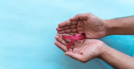 holding maroon colour ribbon Oral Head and Neck Cancer Awareness Week concept image 