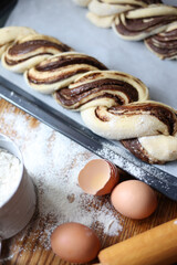 braid with chocolate, raw dough for a bun with chocolate. Freshly baked chocolate swirl pastry - babka. Baker make buns from dough with poppy and chocolate filling. Cooking twisted pie. Top view