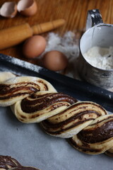 braid with chocolate, raw dough for a bun with chocolate. Freshly baked chocolate swirl pastry - babka. Baker make buns from dough with poppy and chocolate filling. Cooking twisted pie. Top view