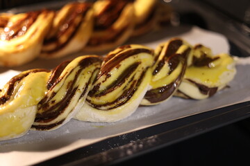 braid with chocolate, raw dough for a bun with chocolate. Freshly baked chocolate swirl pastry - babka. Baker make buns from dough with poppy and chocolate filling. Cooking twisted pie. Top view