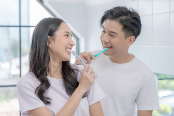 Happy Asian couple brushing their teeth in the bathroom in the morning.