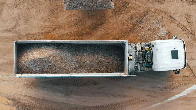 Aerial top down view of an excavator loading crushed stone into a dump truck in a crushed stone quarry