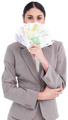 Young businesswoman hiding her face behind bank notes