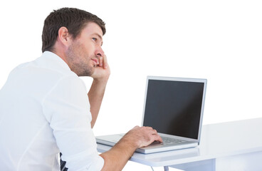 Thinking businessman sitting at desk using laptop