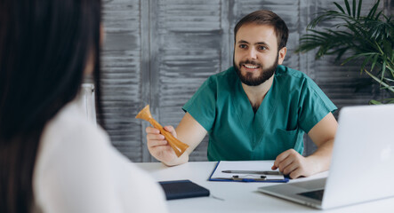 Smiling young Caucasian male doctor in medical uniform consult female patient