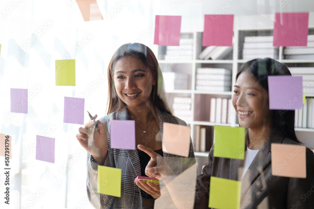 Poster Young busineswoman with team brainstorming by use post it notes to share idea on glass wall.