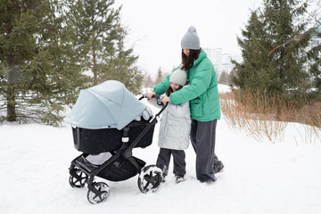 Young mother and daughter with stroller in winter
