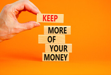 Keep more of your money symbol. Concept words Keep more of your money on wooden block. Beautiful orange table orange background. Businessman hand. Business keep more of your money concept. Copy space.