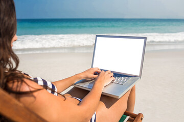 Pretty brunette using laptop on deck chair