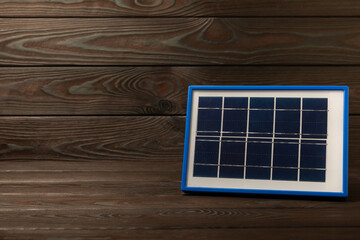 Flat lay composition with solar panel on brown texture wood. The concept of saving money and clean energy. The concept of ecology and sustainable development.