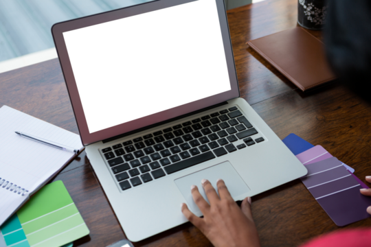 Cropped hand of woman using laptop at home