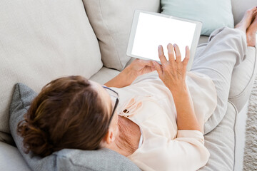 Obraz na płótnie Canvas Woman using digital tablet while lying on sofa