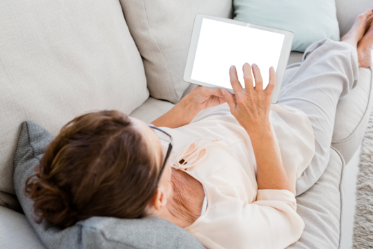 Woman using digital tablet while lying on sofa