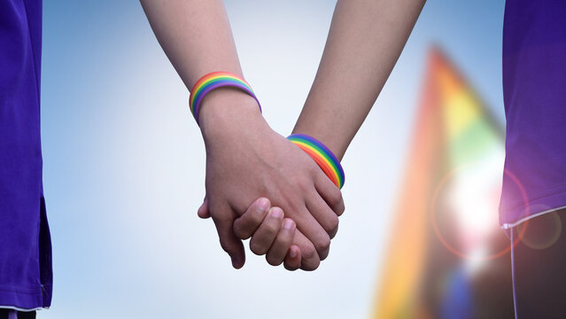Human hands which wear rainbow wristband around them, concept for LGBT people celebration in pride month, June, around the world.