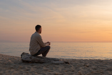 young man with shirt, watching the sunset on a beach