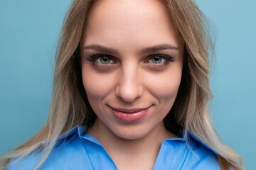 portrait of an adorable blonde young woman cutely closing her eyes on a blue background
