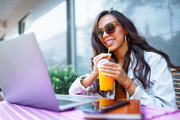 Young and cheerful woman on the terrace chatting on Skype, talking on a webcam, having a video...