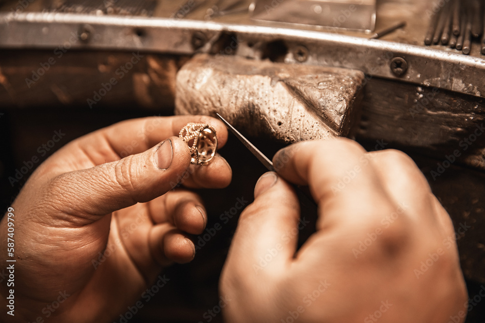 Wall mural Close up of a goldsmith's hand making a gold or silver ring or a diamond using goldsmith's tools. Making ring with diamonds