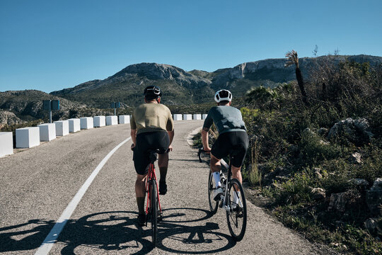 Two cyclists training on Vall d'Ebo pass.Cycling in the spanish mountains.Cyclists in helmets and cycling wear conquer Vall d'Ebo pass.Sport motivation.Cycling professional group ride.Beautiful view.