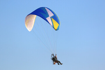 	
Paramotor pilot flying in a blue sky	