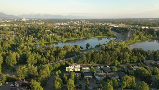 Aerial Establishing shot of a neighborhood in Anchorage, Alaska. Bird's eye view of residential houses. North American city, town, suburb. Summer, sunny, sunset