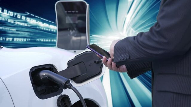 Progressive man check electric car's battery status with smartphone at charging station with technology background of binary code flying through votex. EV car concept with modern technology.