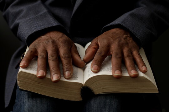 praying to God with hand on the bible on black background stock photo