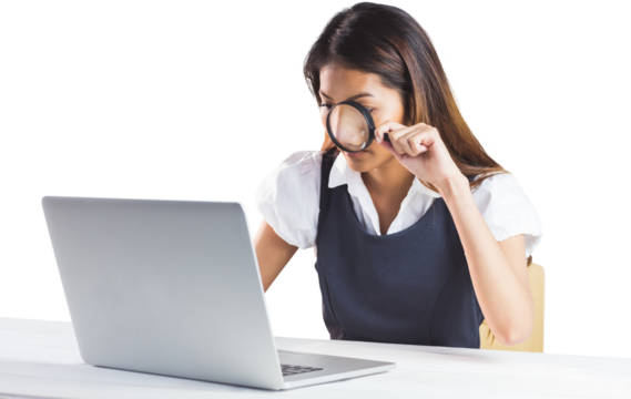 Businesswoman looking through magnifying glass and using laptop