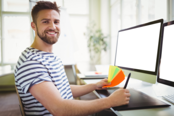 Portrait of man sitting by computer monitor