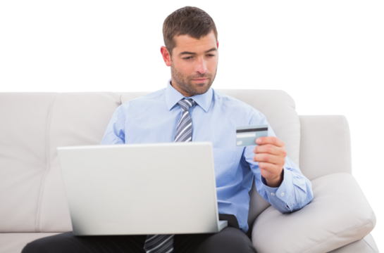Businessman with credit card and laptop sitting on sofa - Powered by Adobe